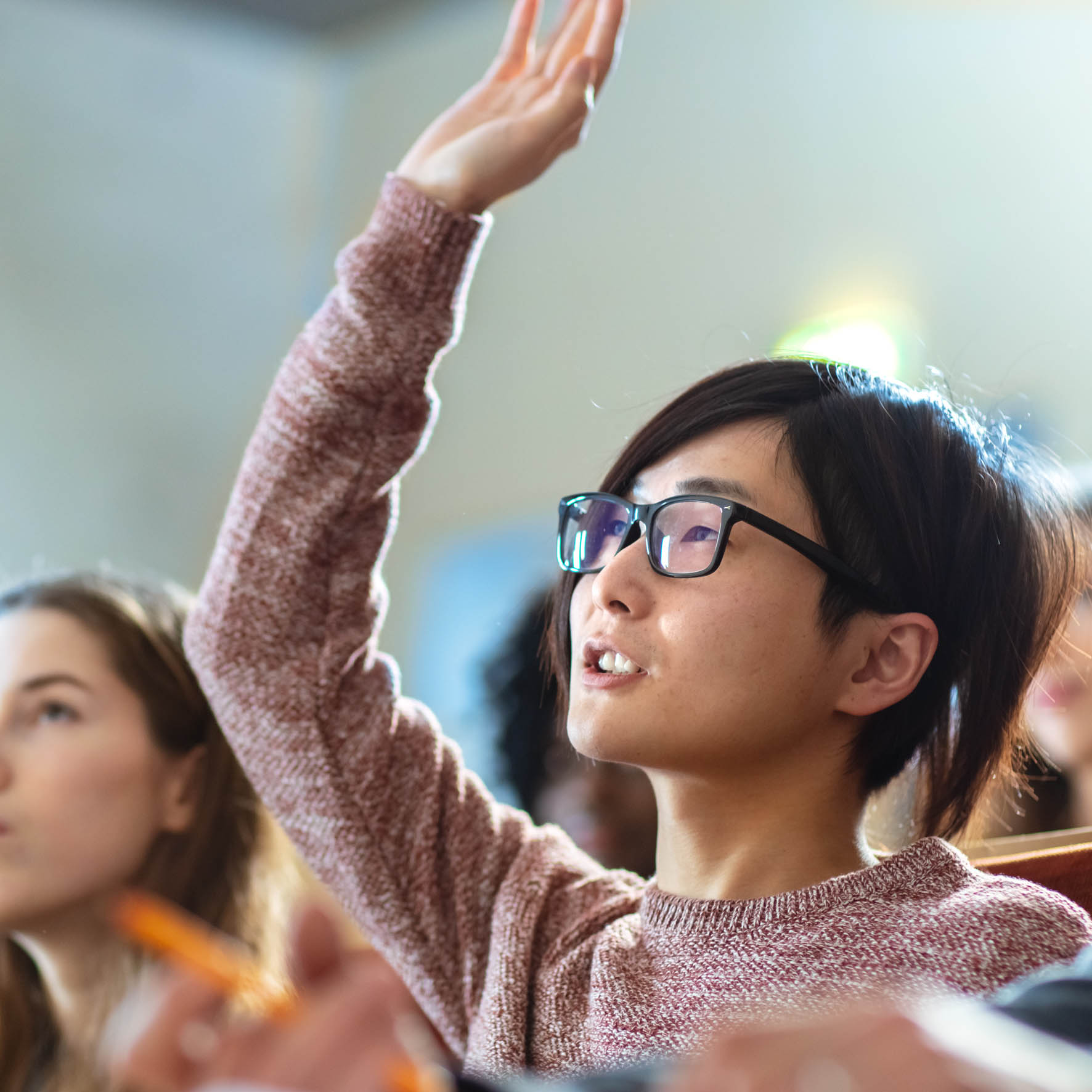 International student raising hand in classroom to ask a question