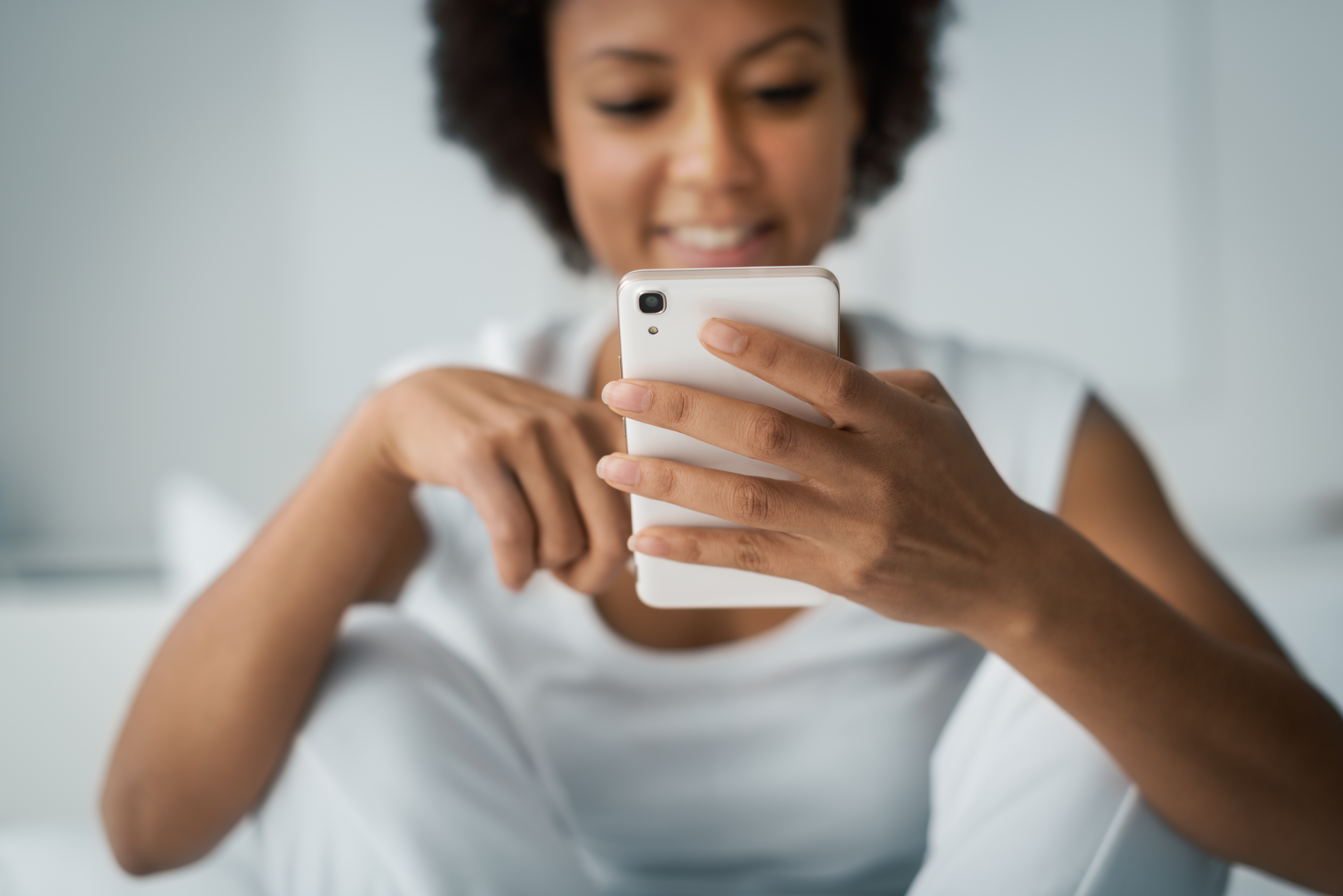 Woman Smiling At Phone After Receiving Business Text Message