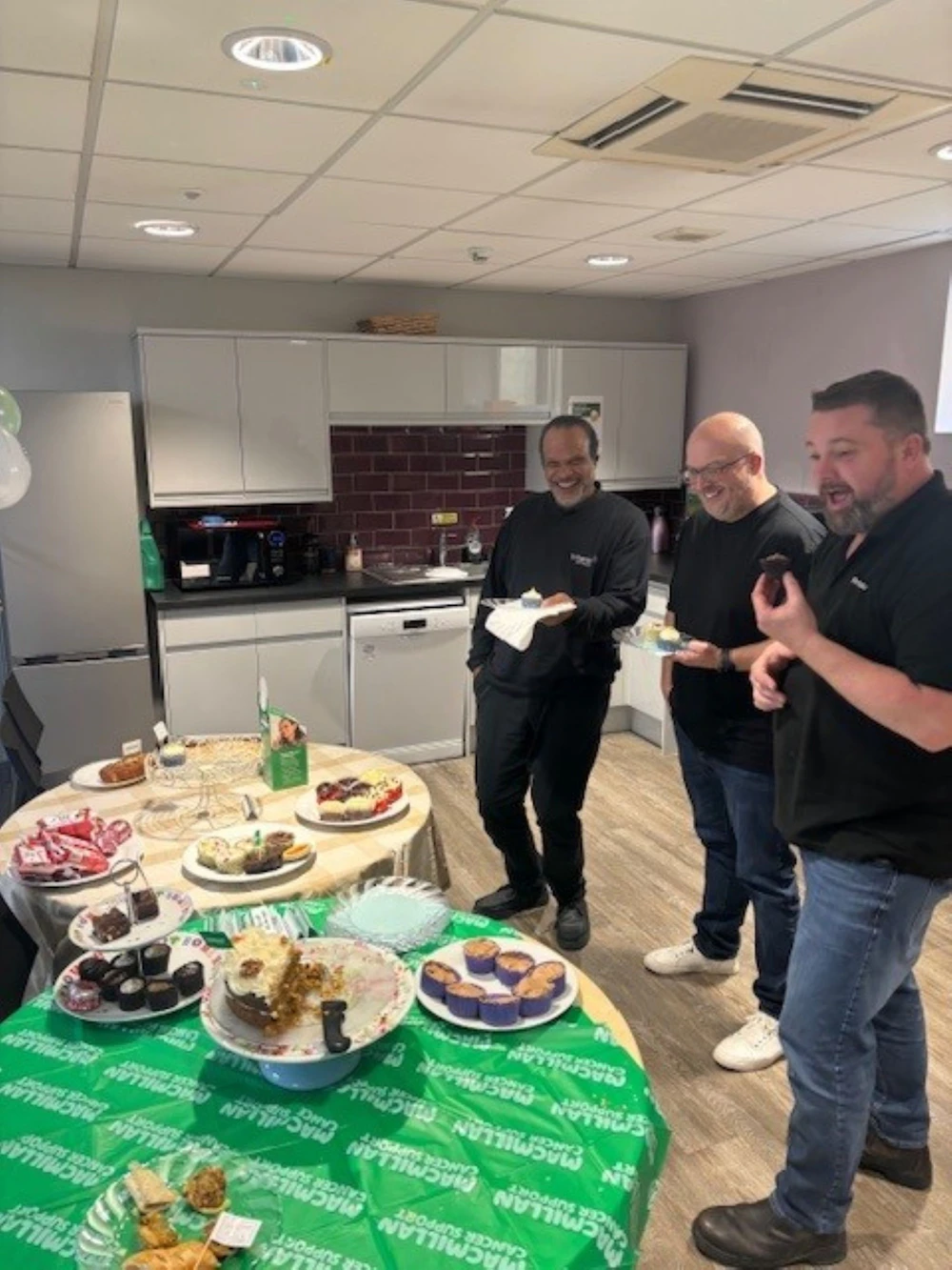 people standing in kitchen eating cake and chatting