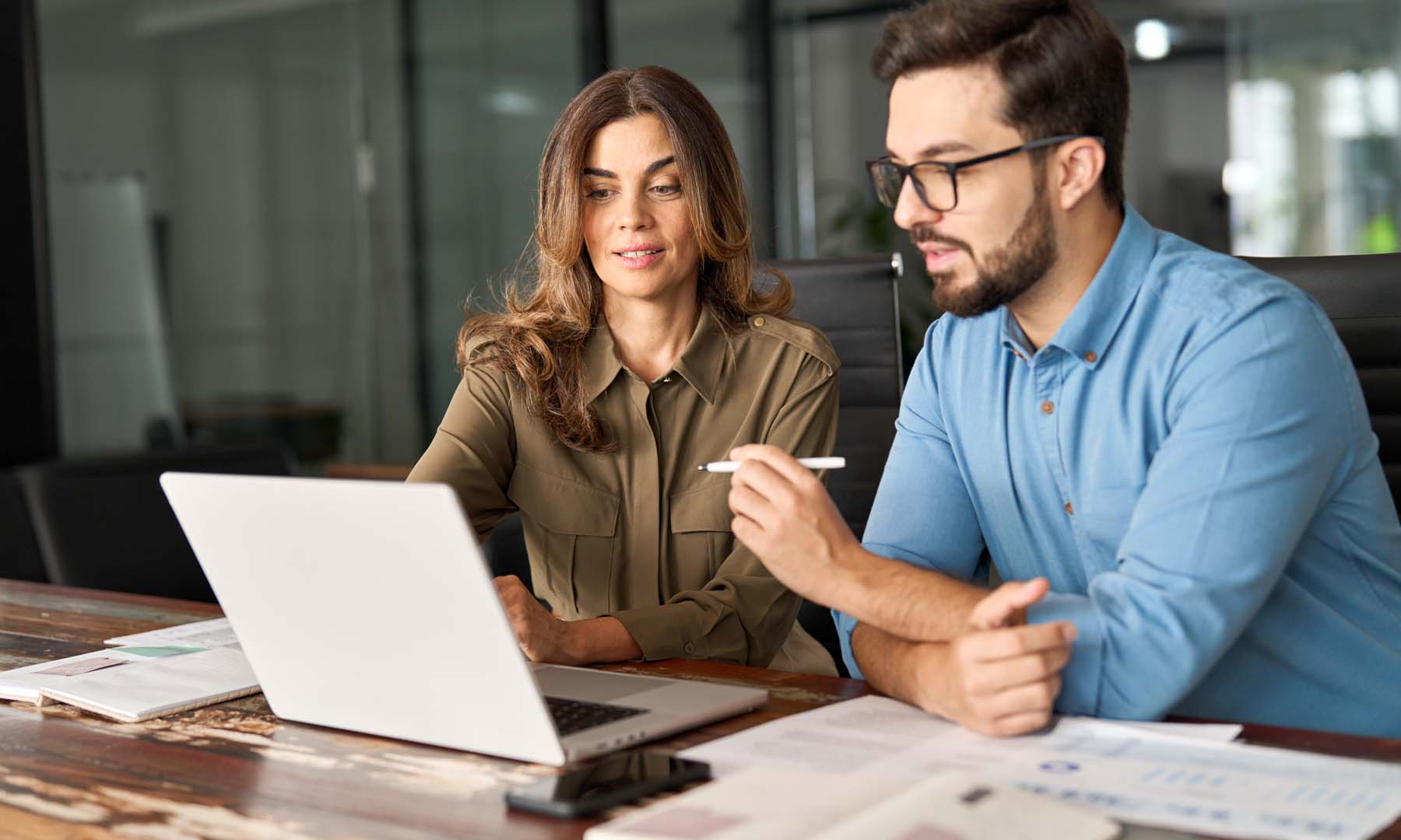 man and woman looking at laptop discussing business notes