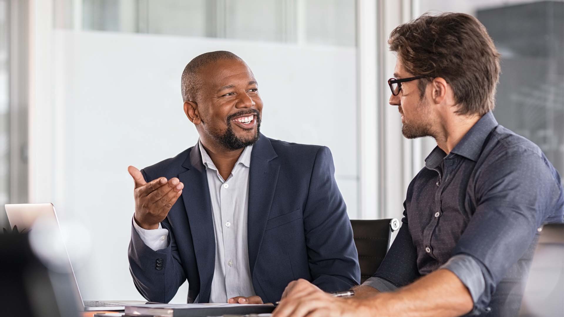 Two Men At A Desk Discussing Products
